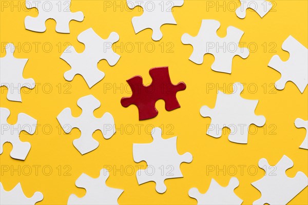 Red bright puzzle among white against yellow backdrop