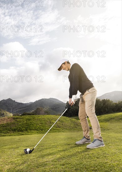 Side view man playing golf field with club copy space