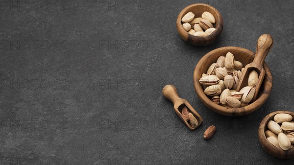 Pistachio nuts bowls with wooden spoons copy space