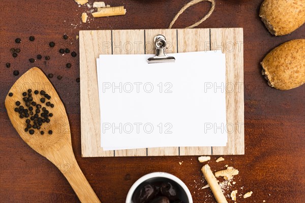 Top view blank white paper with clipboard bun bread sticks peppercorn with spatula wooden desk