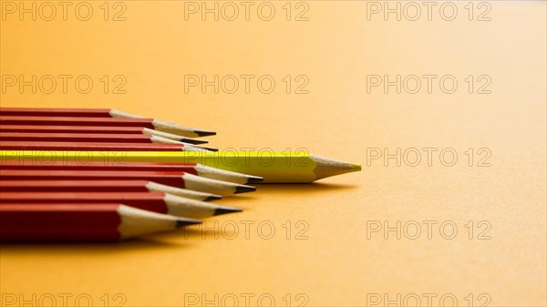 Yellow colored pencil lying red pencil against yellow background