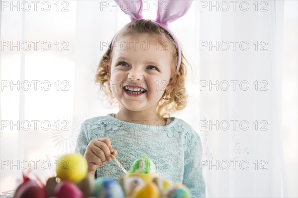 Girl painting egg looking up