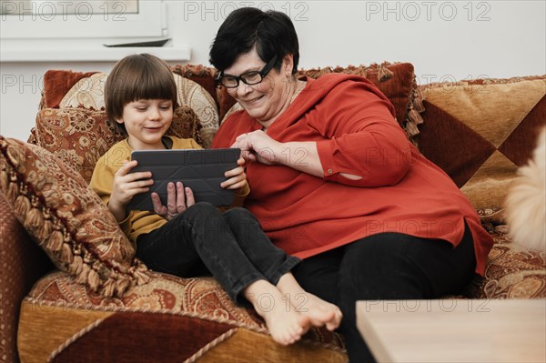 Smiley grandmother playing with grandson tablet