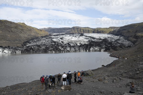 Mountaineers and tourists in front of Solheimajoekull glacier and glacial lake
