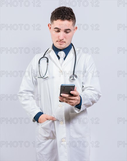 Handsome doctor using phone on isolated background. Young latin doctor holding telephone isolated