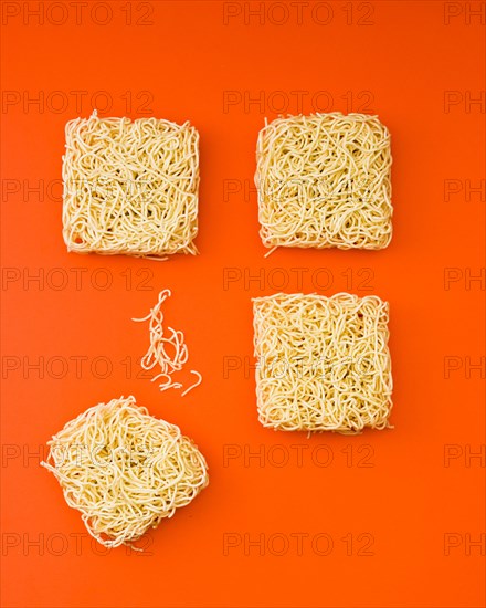 Dried instant noodle blocks arranged orange backdrop