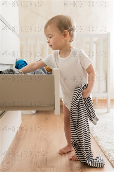 Full shot baby taking clothes from drawer