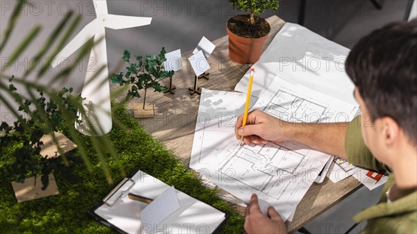 High angle man working eco friendly wind power project with paper plans