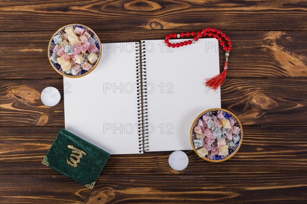 Overhead view spiral notebook with delight lukum bowls kuran red prayer beads wooden desk