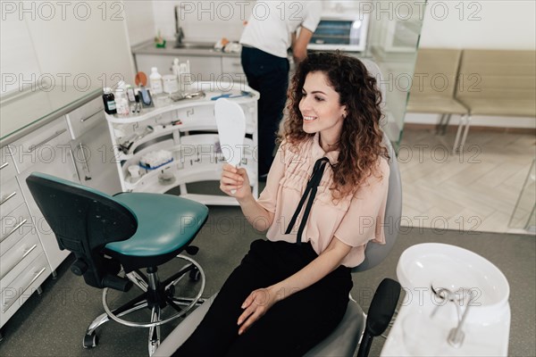 Woman looking teeth mirror dentist appointment