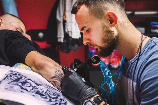 Adult man working with tattoo pen arm