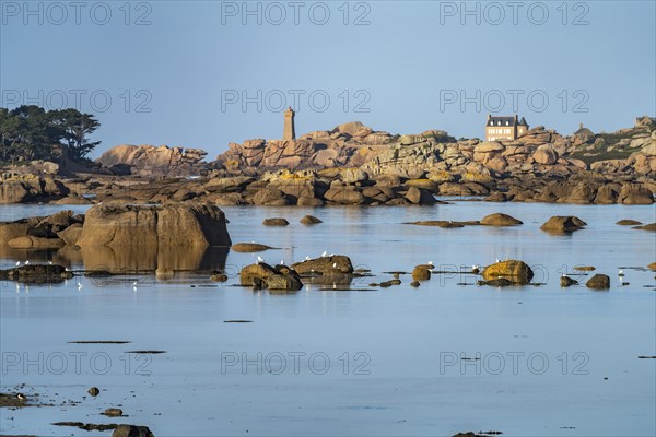 The rocks of the pink granite coast Cote de Granit Rose at the Baie de Sainte Anne near Tregastel with view of the Maison Gustave Eiffel and the lighthouse Phare de Ploumanac'h