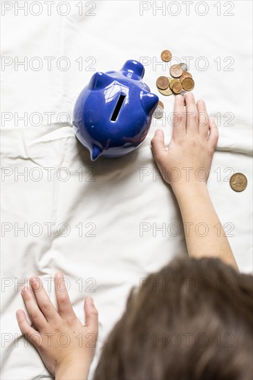 Top view child counting his money from piggy bank
