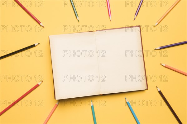 Open sketchbook surrounded by pencils different colors