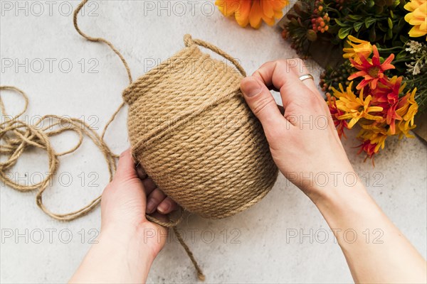 Overhead view woman making string with jute string textured backdrop