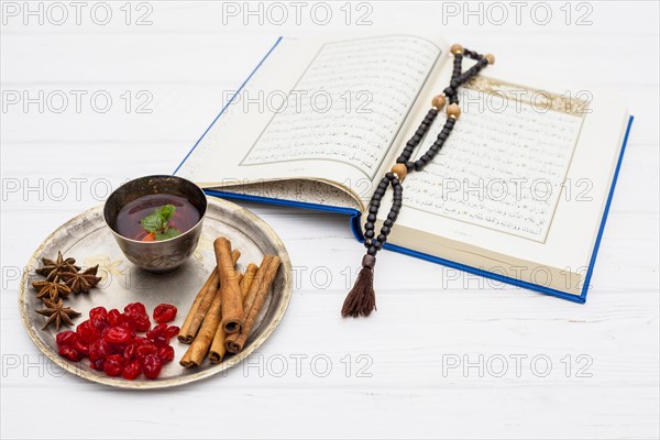 Mug tea near spices tray book with beads