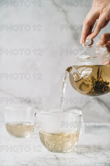 Person pouring tea cups marble background