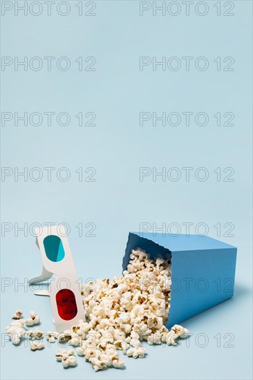 3d glasses with spilled popcorns blue background