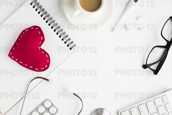 Healthcare accessories with red toy heart spiral notepad white background