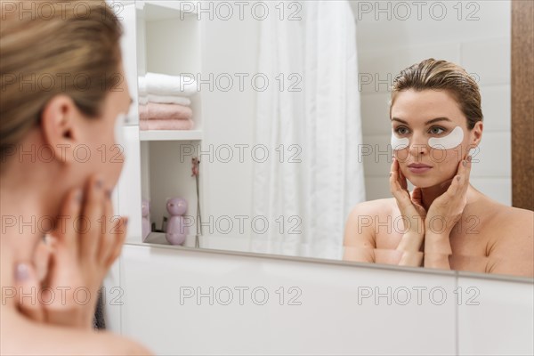 Woman using reducing dark circles patches mirror