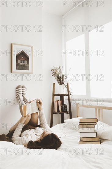 Young woman lying bed with book