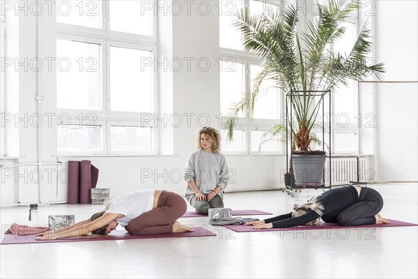 Teacher watching women doing yoga