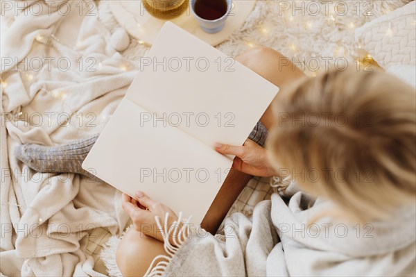 Woman reading book while enjoying winter holidays