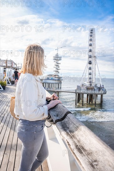 Tourist standing on the pier looking at the Ferris wheel