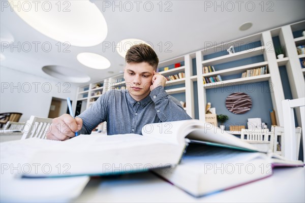 Student reading with books table library