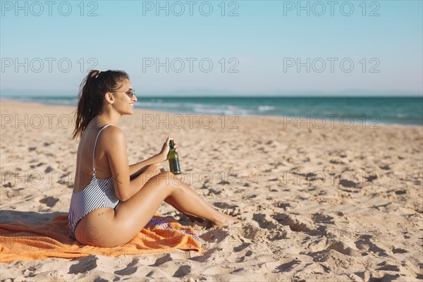 Smiling young woman relaxing beach with beer