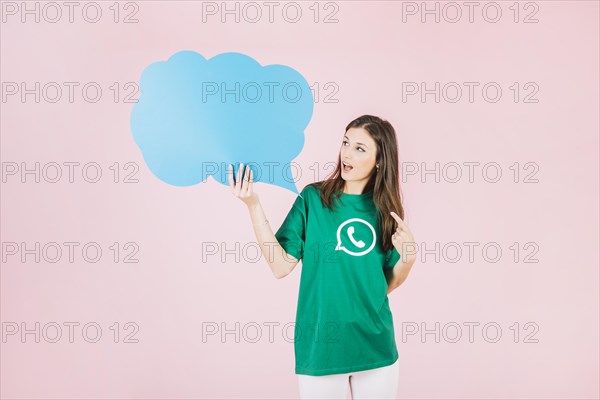 Young woman holding empty blue speech bubble pink background