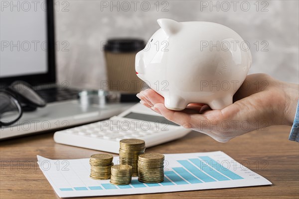 Hand holding piggy bank with growth chart coins