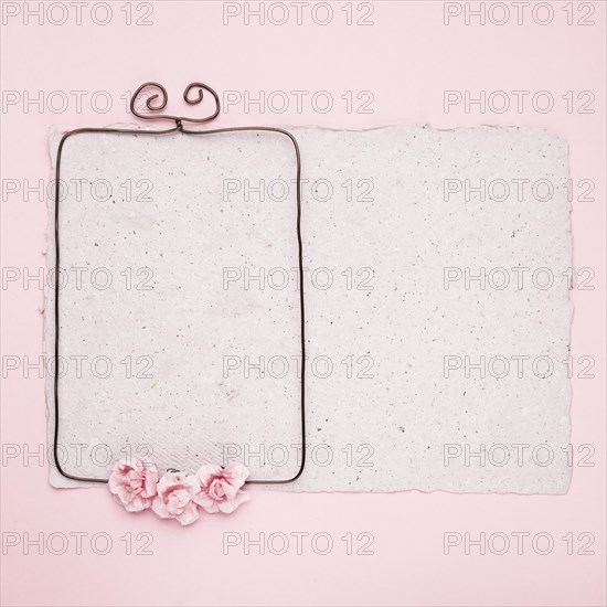 Rectangular wire frame decorated with roses paper against pink background