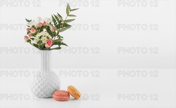 Vase with flowers macarons beside