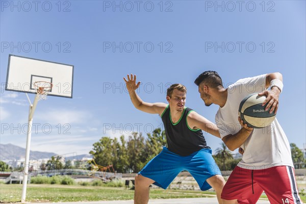 Young male player playing with basketball player