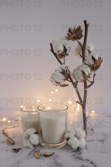 Candles decorated with cotton twig lighting equipments marble surface