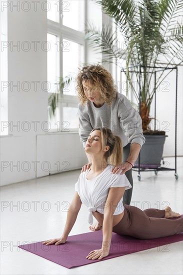 Yoga teacher helping woman