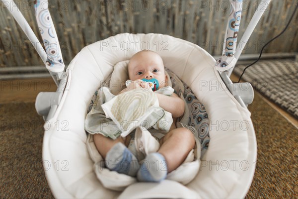 Cute baby with pacifier lying baby carriage home