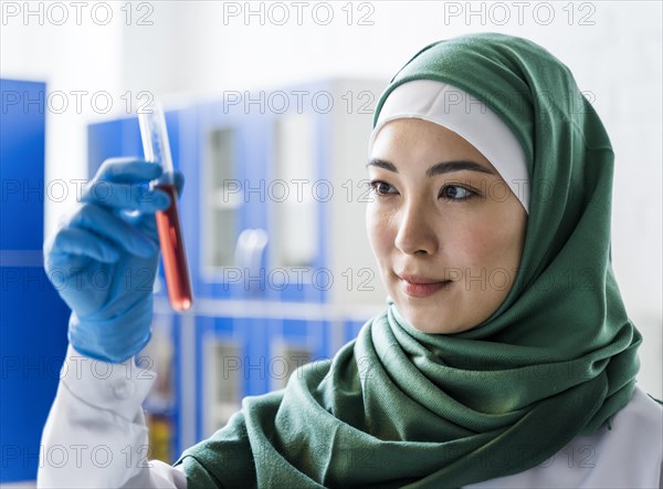 Side view female scientist with hijab holding substance