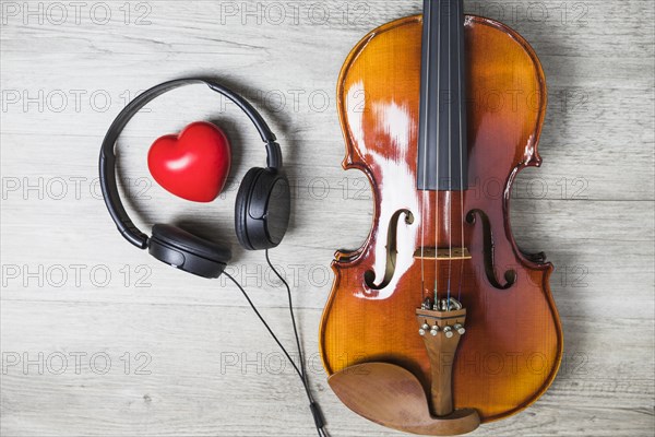 Elevated view red heart surrounded with headphone wooden classical guitar gray table