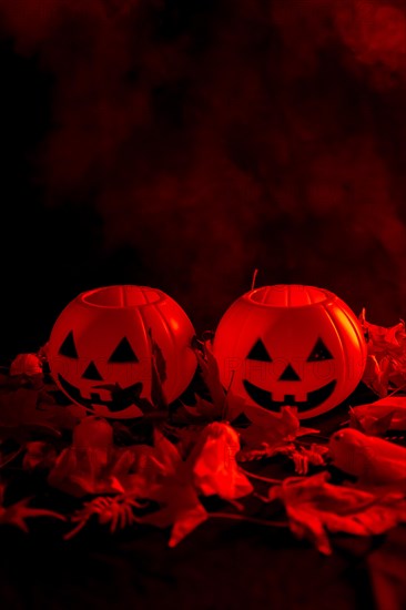 Halloween pumpkins on autumn leaves with smoke on a red background