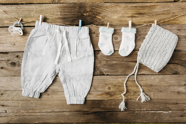 Baby s pant socks headwear pacifier hanging clothesline with clothespins against wooden wall