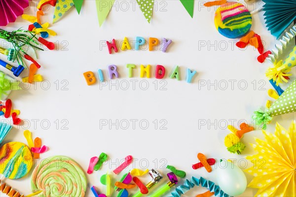 Elevated view happy birthday text with party accessories white surface