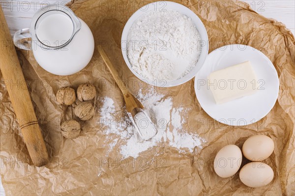 Top view eggs cheese flour walnuts rolling pin brown crumpled paper