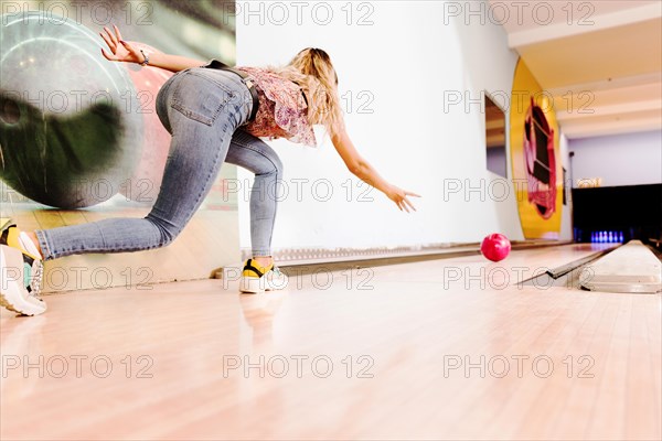 Low view woman throwing bowling ball