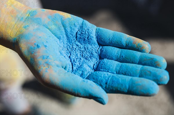 Close up person s hand holding blue holi color