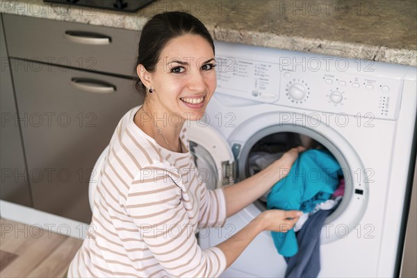 Lady putting clothes washing machine