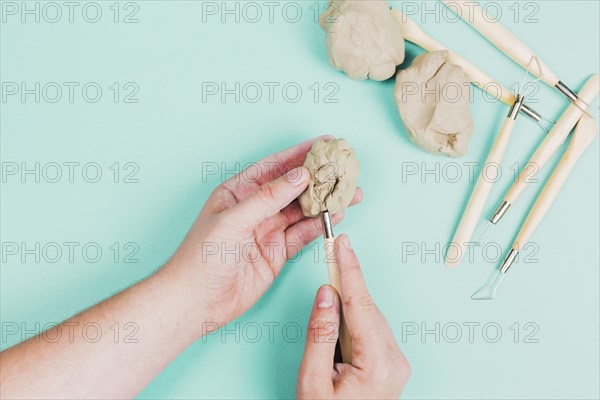 Close up person s hand using sculpting tools mint green background