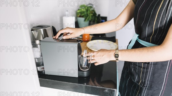 Woman holding glass mug coffee machine kitchen