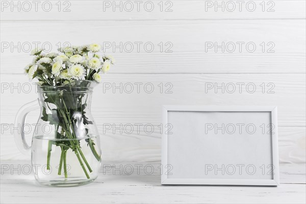 Chrysanthemum flower glass jug against blank frame wooden backdrop